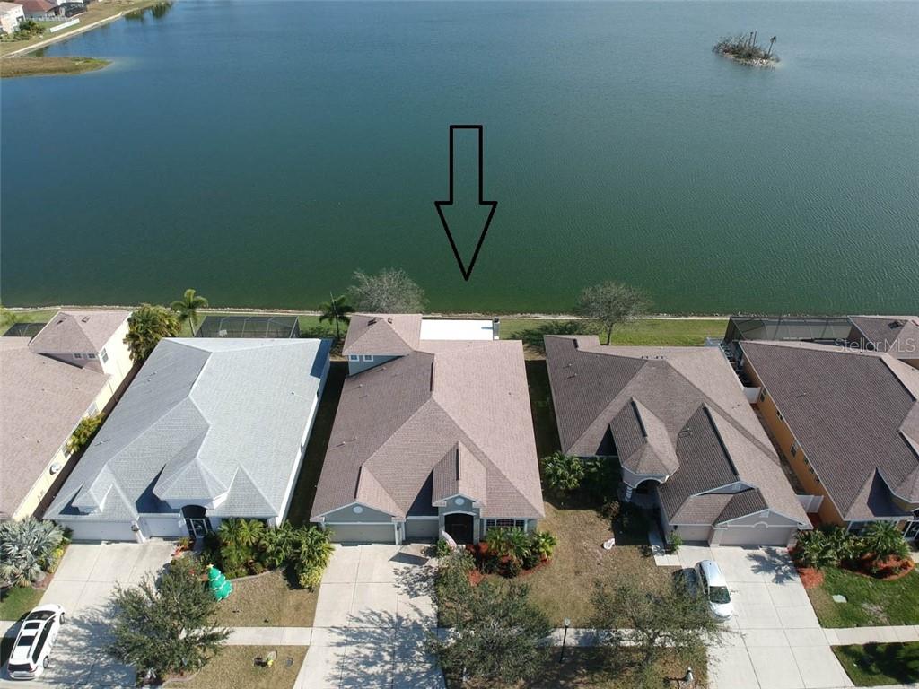 An aerial view shows a suburban house with a backyard patio facing a lake — 1742 MIRA LAGO CIRCLE, RUSKIN, FL