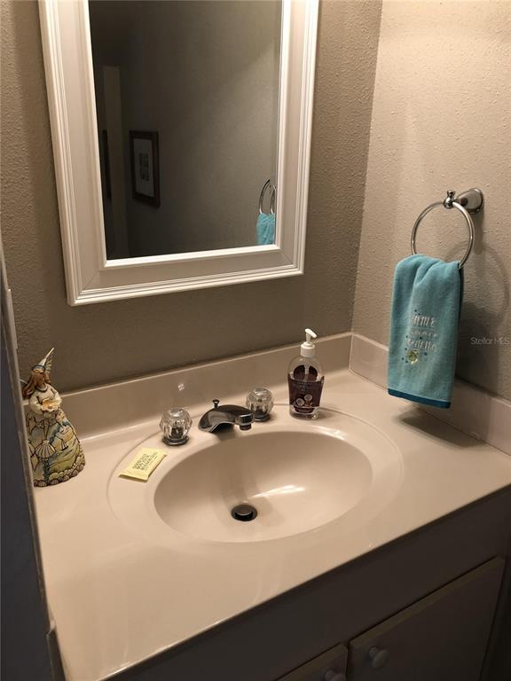 A bathroom vanity features a white-framed mirror, a beige countertop, and a blue hand towel — 815 OCEAN SHORE BOULEVARD UNIT 8B, ORMOND BEACH, FL