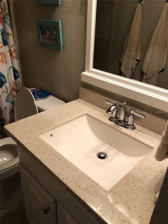 A bathroom features a white vanity sink with a speckled countertop and a wall mirror — 815 OCEAN SHORE BOULEVARD UNIT 8B, ORMOND BEACH, FL