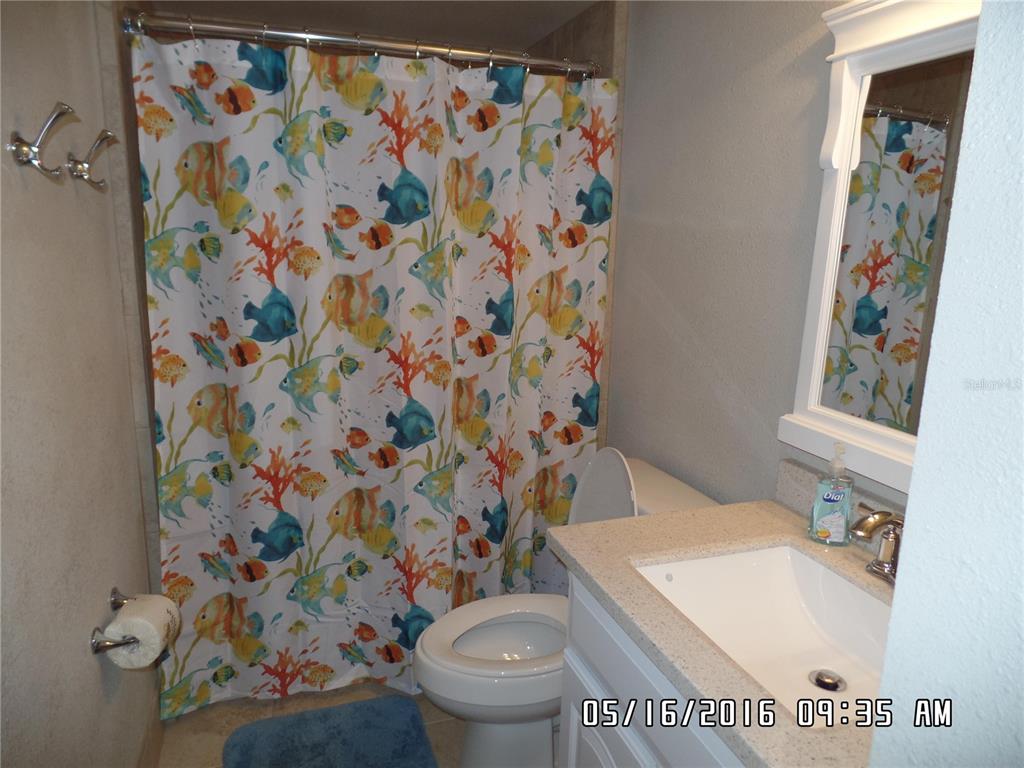 A bathroom features a fish-patterned shower curtain, a white vanity with a sink, and a toilet — 815 OCEAN SHORE BOULEVARD UNIT 8B, ORMOND BEACH, FL