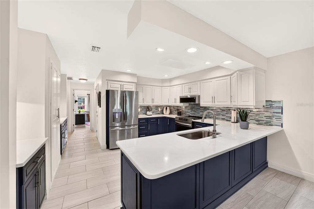 A kitchen with a blue island, white countertops, white upper cabinets, and light tile flooring — 9636 SW 190TH TERRACE ROAD, DUNNELLON, FL