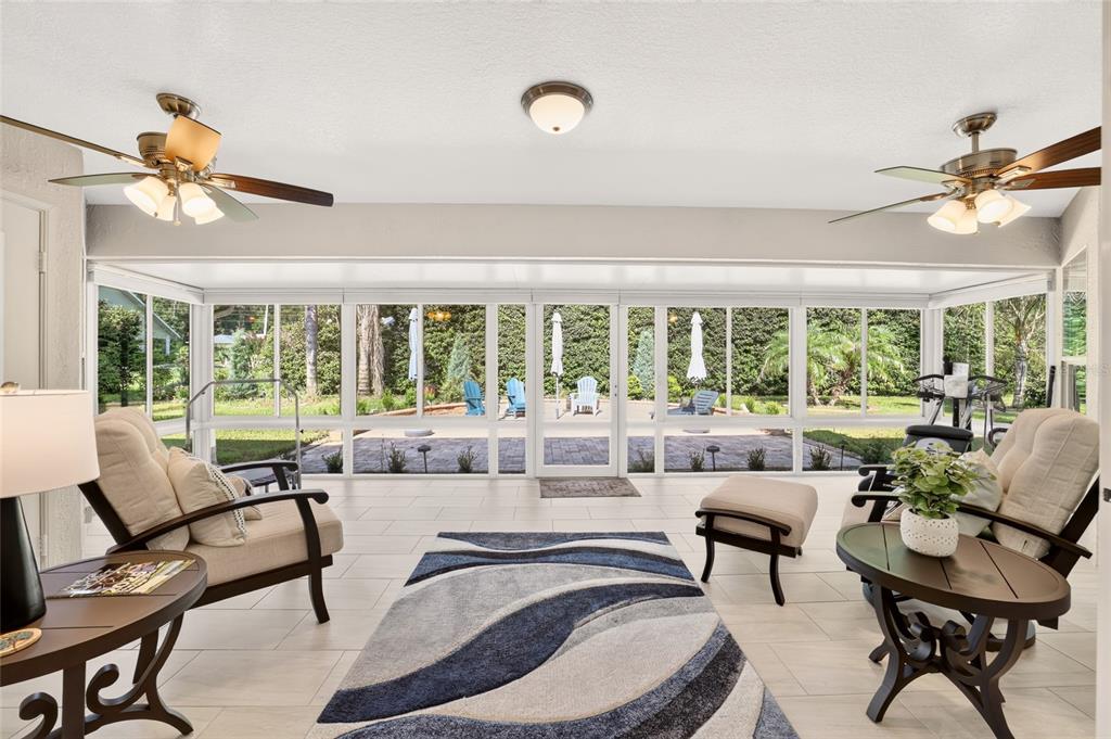 A sunroom with tile flooring, two ceiling fans, and a view of the backyard patio — 9636 SW 190TH TERRACE ROAD, DUNNELLON, FL