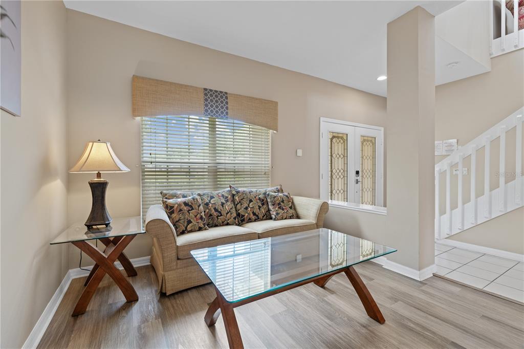A living room features a beige sofa, glass-topped tables, and a staircase near the entrance — 602 HIGHGATE PARK, DAVENPORT, FL