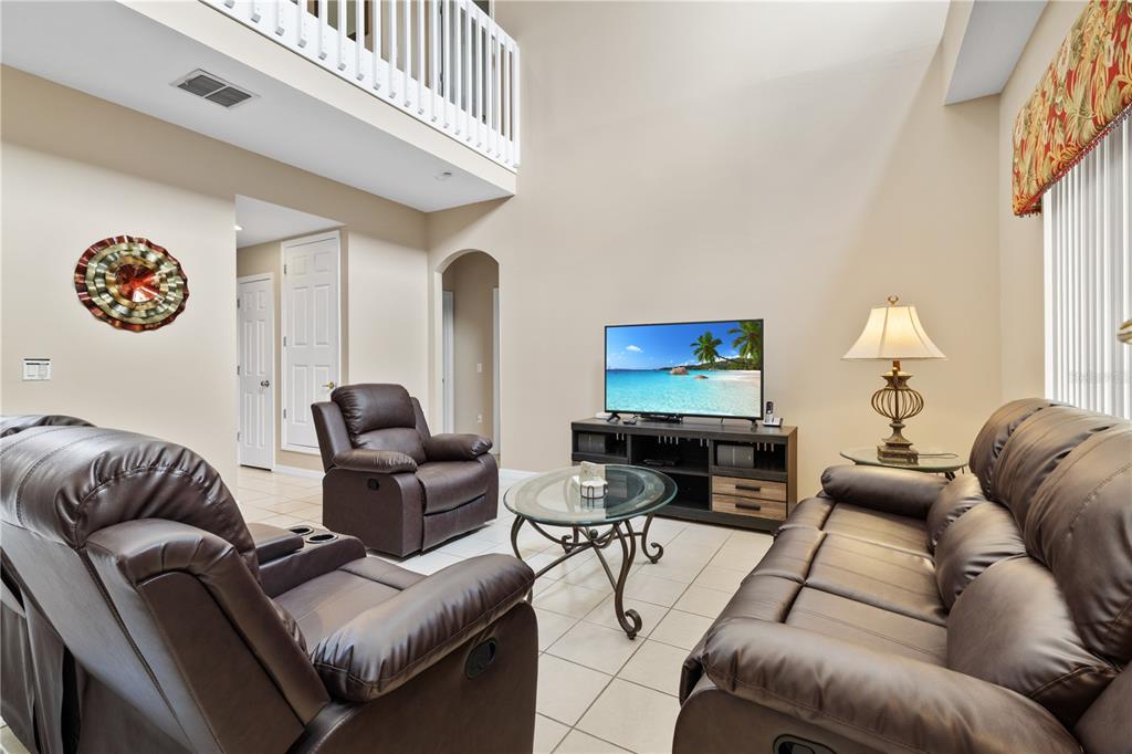 A living room features brown leather furniture, a glass coffee table, and a television console — 602 HIGHGATE PARK, DAVENPORT, FL