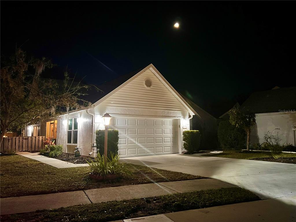 A single-story house with a white garage and driveway at night under a full moon — 7801 ONTARIO STREET CIRCLE, SARASOTA, FL