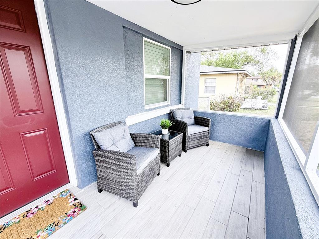 A living room features a white sofa, two patterned armchairs, a glass coffee table, and a television — 1704 MARTIN L KING JR AVENUE, LAKELAND, FL