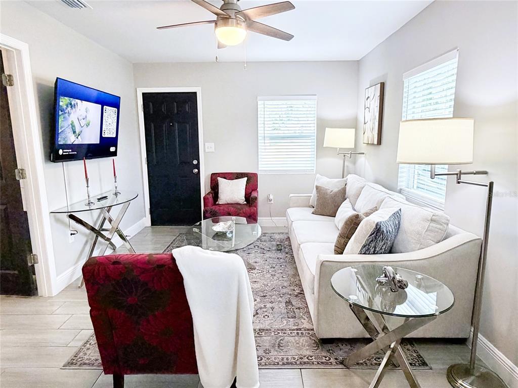 A living room features a white sofa, two patterned red armchairs, and a glass coffee table — 1704 MARTIN L KING JR AVENUE, LAKELAND, FL