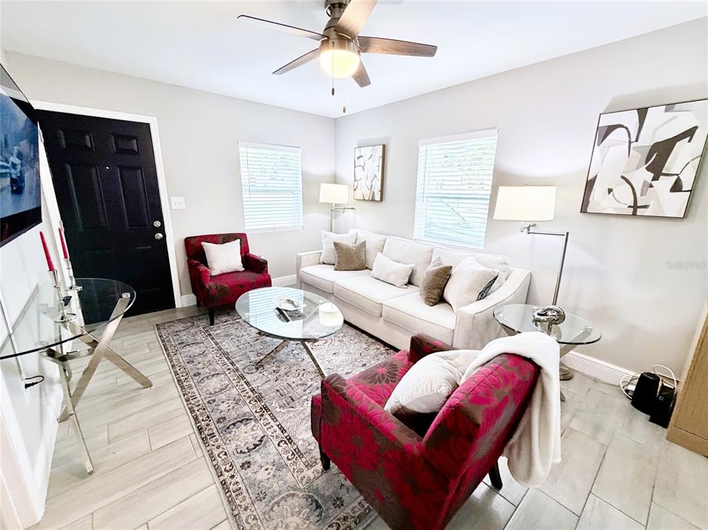 A living room features a white sofa, two patterned armchairs, and a glass coffee table — 1704 MARTIN L KING JR AVENUE, LAKELAND, FL
