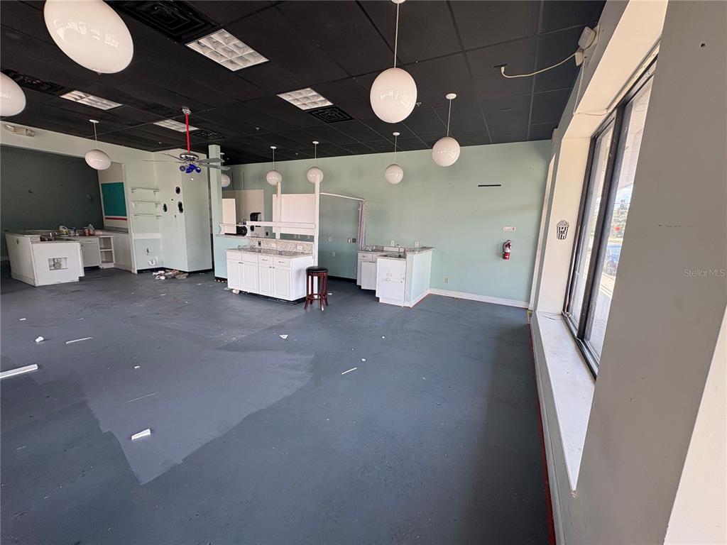 An empty commercial space features a black drop ceiling, pendant lighting, and white cabinetry — 80 N CENTRAL AVENUE, UMATILLA, FL