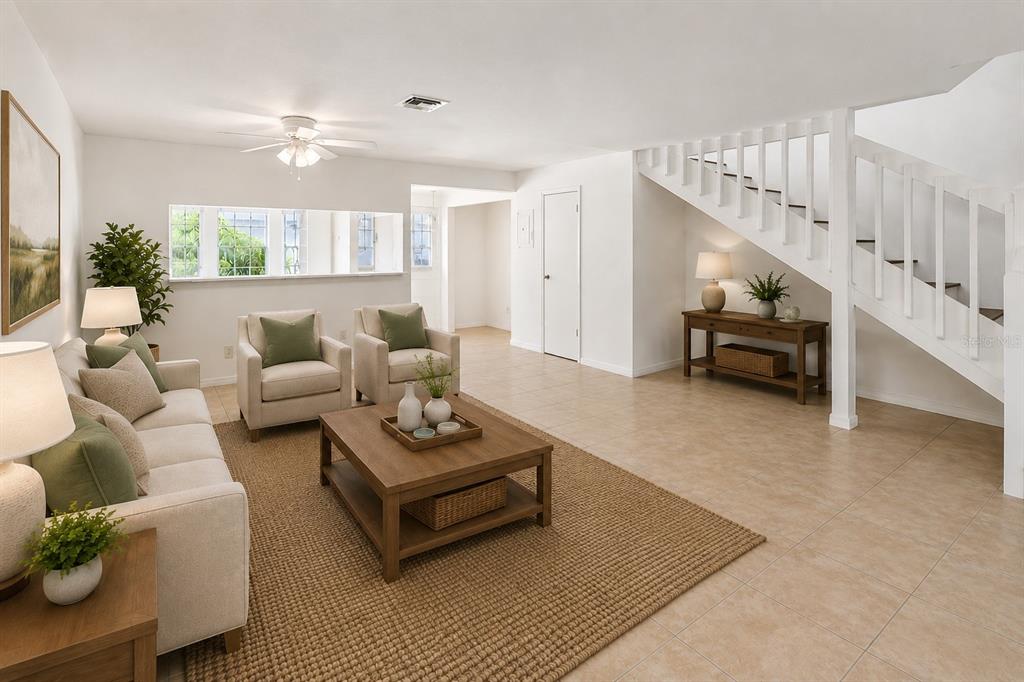 A living room features tile floors, a wooden coffee table, and a staircase with railings — 5989 BRAEMAR PLACE UNIT 102, ORLANDO, FL