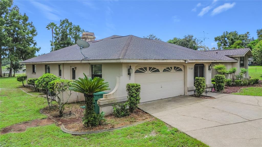 A single-story house with a beige stucco exterior, a two-car garage, and a concrete driveway — 7520 E POCONO DRIVE, INVERNESS, FL