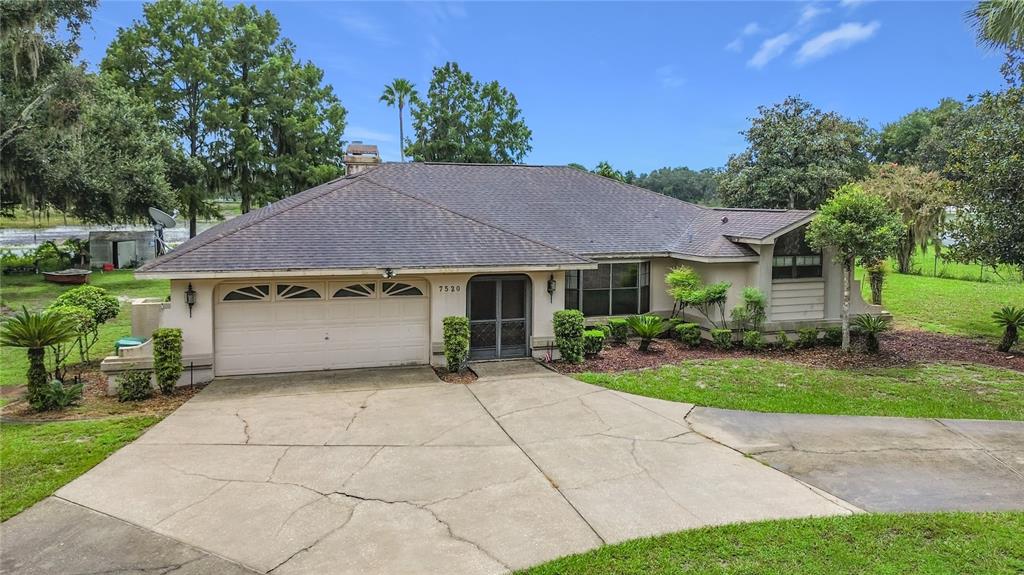 A single-story house with a beige stucco exterior, a two-car garage, and a concrete driveway — 7520 E POCONO DRIVE, INVERNESS, FL