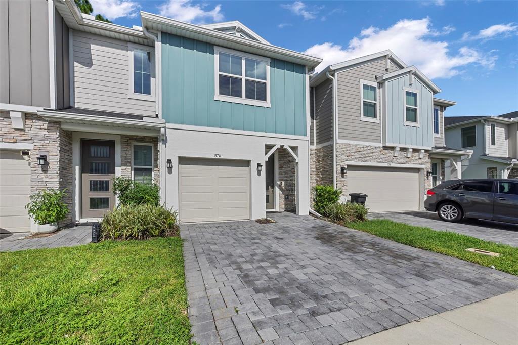 A two-story townhouse with a stone facade, teal siding, and a paved driveway — 1370 CAPTIVA COVE, SANFORD, FL