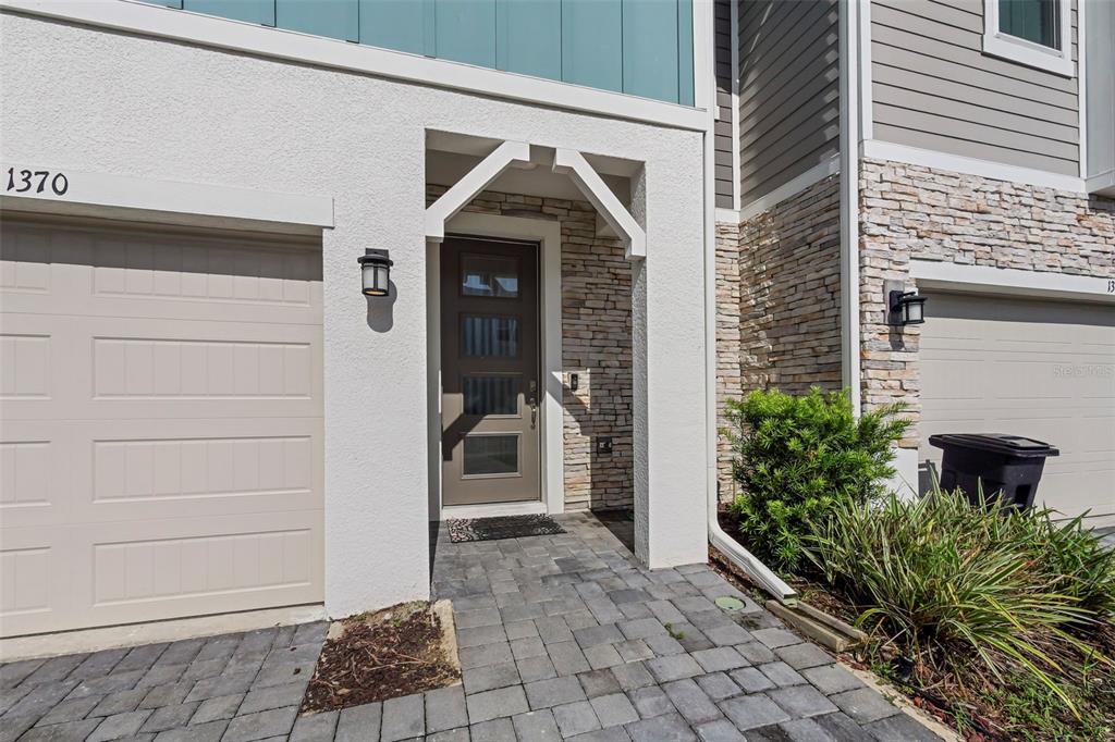 The exterior of a townhouse features a stone-accented entryway, a front door, and garage doors — 1370 CAPTIVA COVE, SANFORD, FL