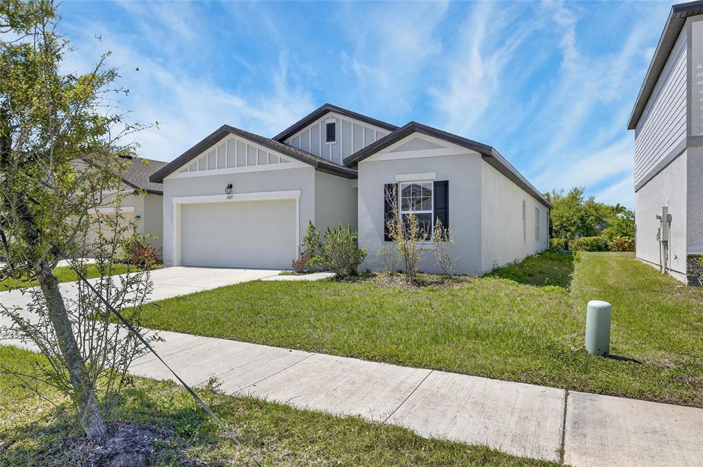 A single-story suburban house with a two-car garage, light gray stucco, and a gabled roof — 1363 ANCHOR BEND DRIVE, RUSKIN, FL