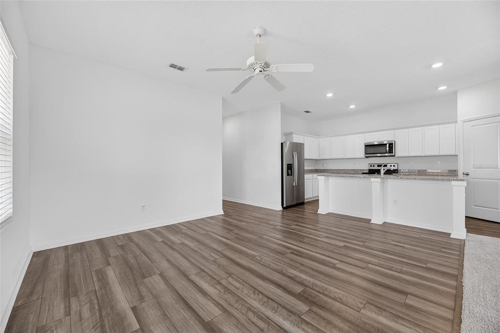 An open-concept living area features wood-look flooring, a ceiling fan, and a kitchen with white cabinets — 1363 ANCHOR BEND DRIVE, RUSKIN, FL
