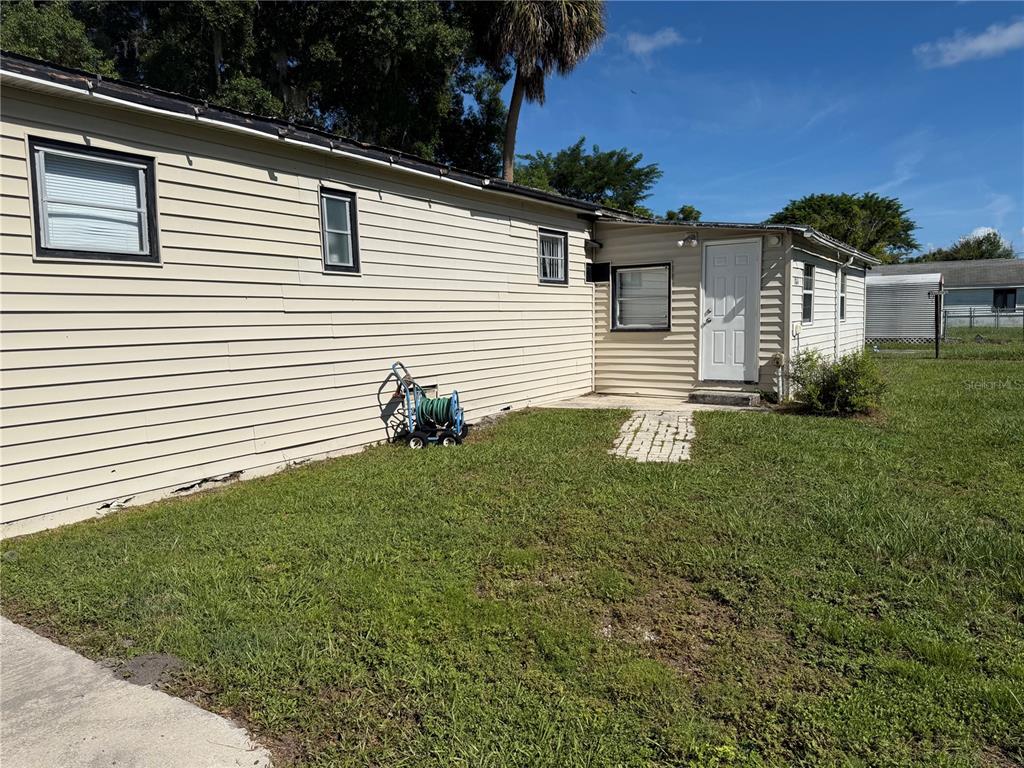 A beige mobile home exterior features horizontal siding, a white door, and a hose reel — 1814 KENTUCKY AVENUE, ST CLOUD, FL