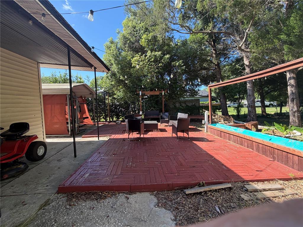 An outdoor patio features red modular decking, a seating area, and a raised garden bed — 1814 KENTUCKY AVENUE, ST CLOUD, FL