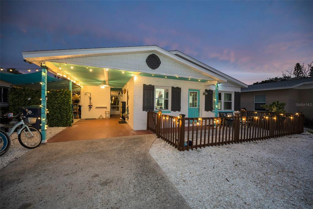 A white brick house with a turquoise door, a carport, and a fenced front patio — 305 15TH AVENUE, INDIAN ROCKS BEACH, FL