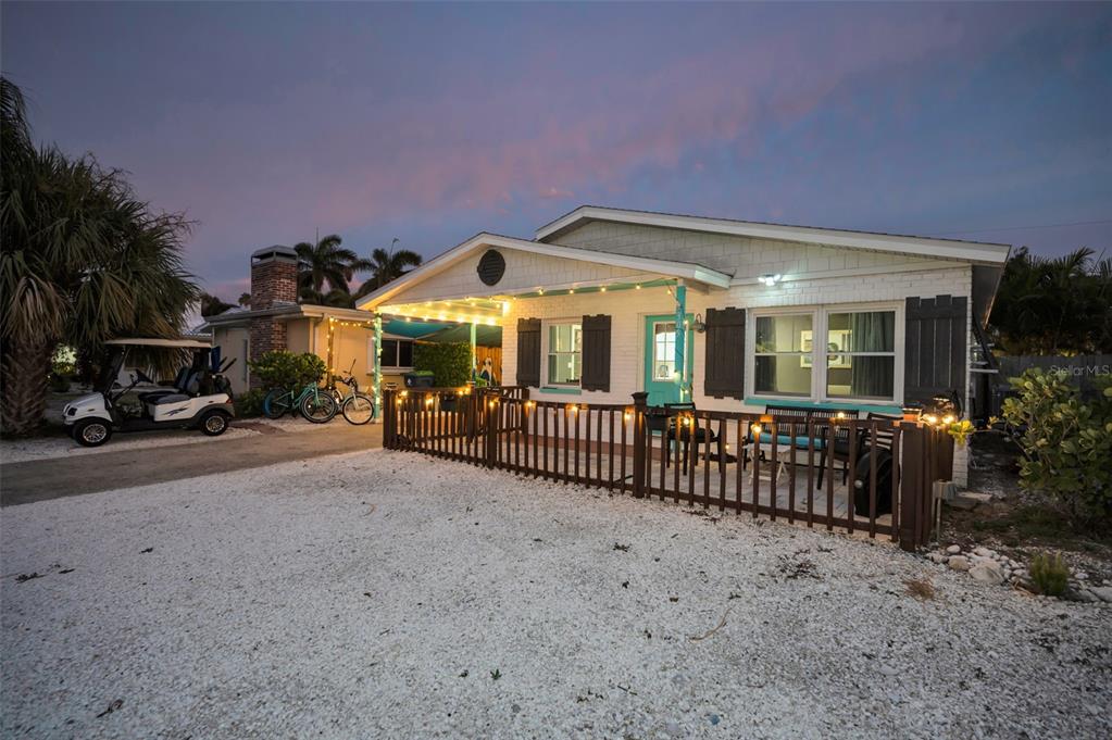A single-story house with a white brick exterior, a wooden porch fence, and string lights — 305 15TH AVENUE, INDIAN ROCKS BEACH, FL