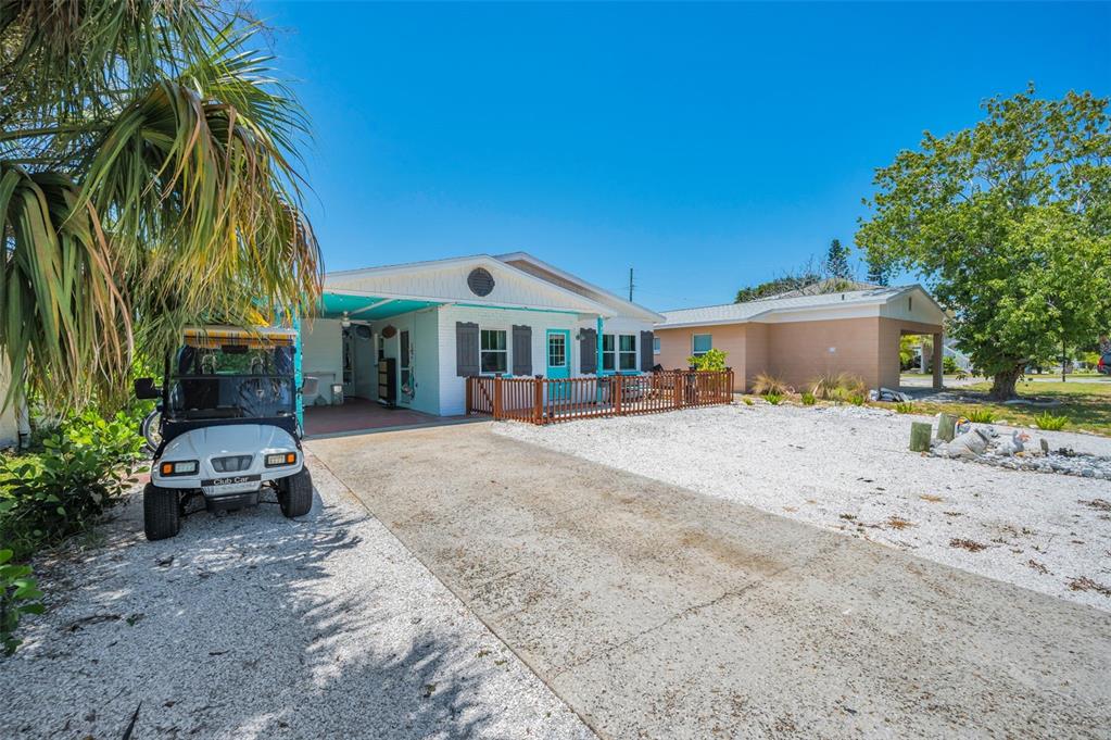 A white house with a turquoise door, a wooden deck, and a golf cart parked outside — 305 15TH AVENUE, INDIAN ROCKS BEACH, FL