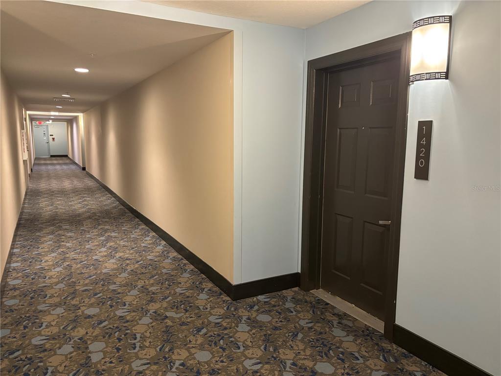 A long hotel-style hallway with patterned carpet leads to a dark door labeled 1420 — 14501 GROVE RESORT AVENUE UNIT 1420, WINTER GARDEN, FL