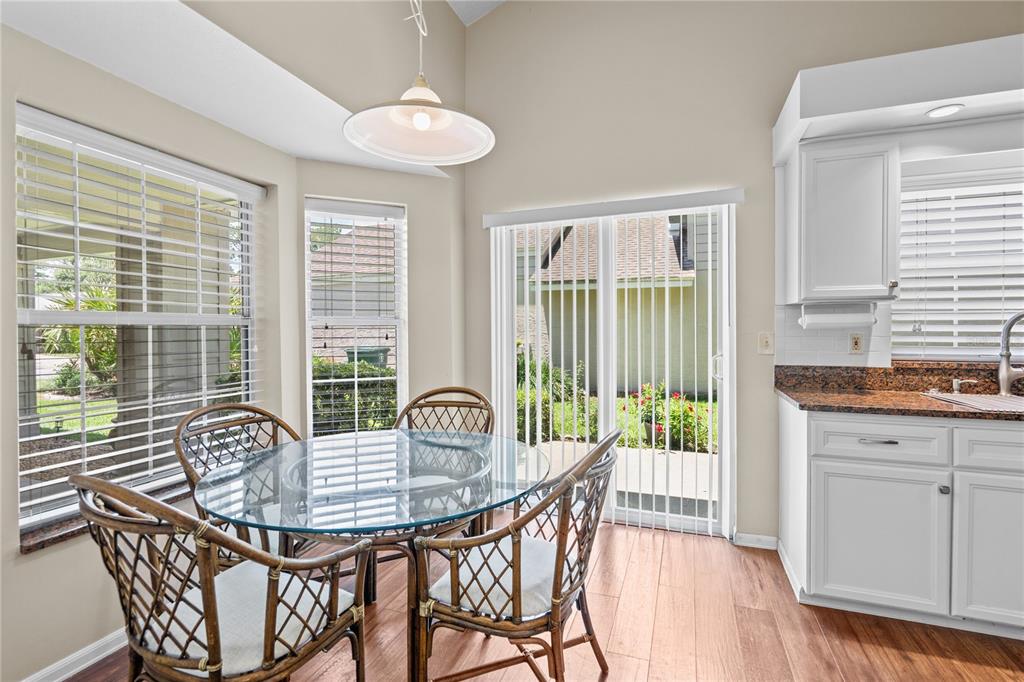 A dining area with a glass table, wicker chairs, and sliding doors leading to a patio — 254 GLENBRIAR CIRCLE, DAYTONA BEACH, FL