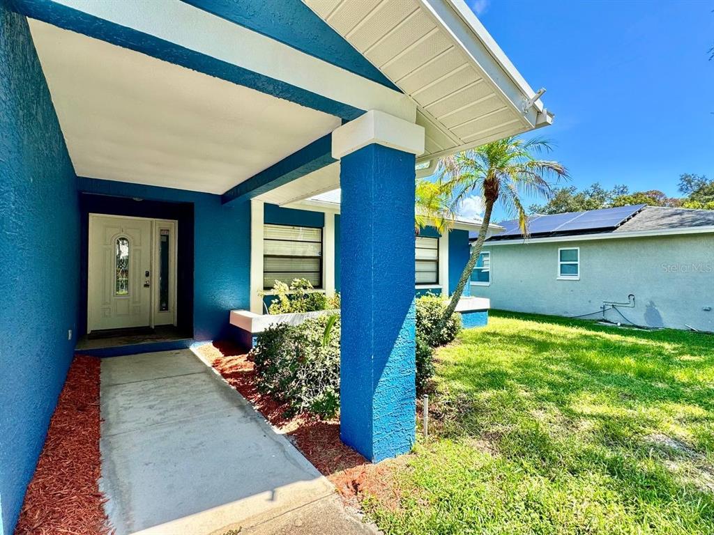 A blue house exterior features a covered front porch, a concrete walkway, and a lawn — 2775 DIANE TERRACE, CLEARWATER, FL