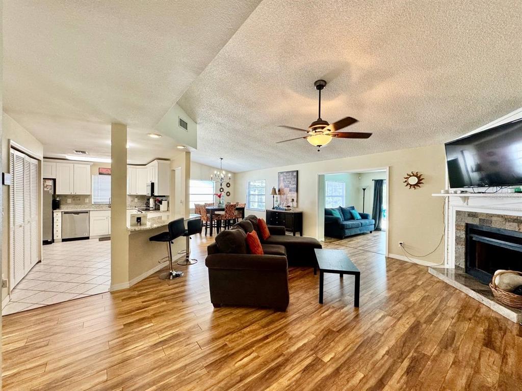 An open-concept living room and kitchen feature wood-look flooring, a fireplace, and a ceiling fan — 2775 DIANE TERRACE, CLEARWATER, FL