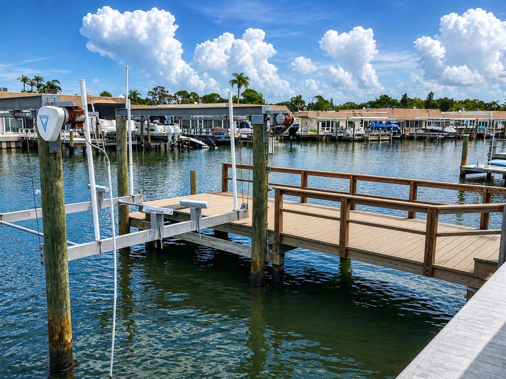 A wooden boat dock with a mechanical lift extends into a canal with moored boats — 365 BOCA CIEGA POINT BOULEVARD, ST PETERSBURG, FL