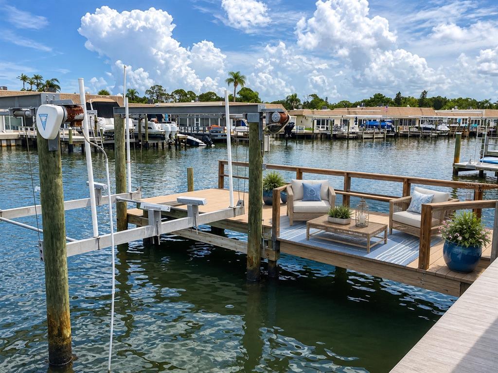 A wooden boat dock features a boat lift, outdoor seating, and a view of water — 365 BOCA CIEGA POINT BOULEVARD, ST PETERSBURG, FL