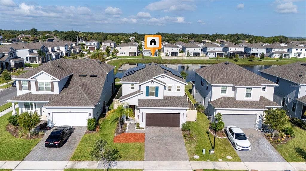 An aerial view shows three suburban houses with driveways and a pond in the background — 1582 SEPAL STREET, KISSIMMEE, FL