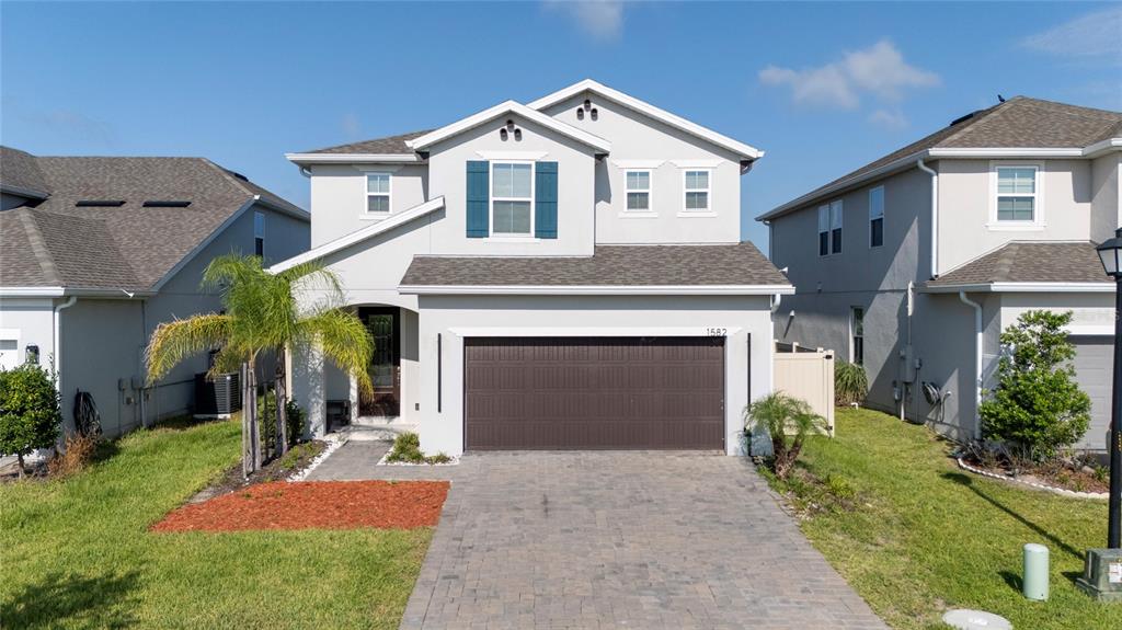 A two-story suburban house features a gray stucco exterior, a brown garage door, and shutters — 1582 SEPAL STREET, KISSIMMEE, FL