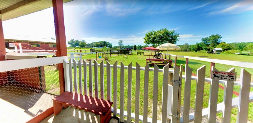 A white picket fence encloses a grassy yard with a picnic table and red umbrella — 11150 W HIGHWAY 40, OCALA, FL