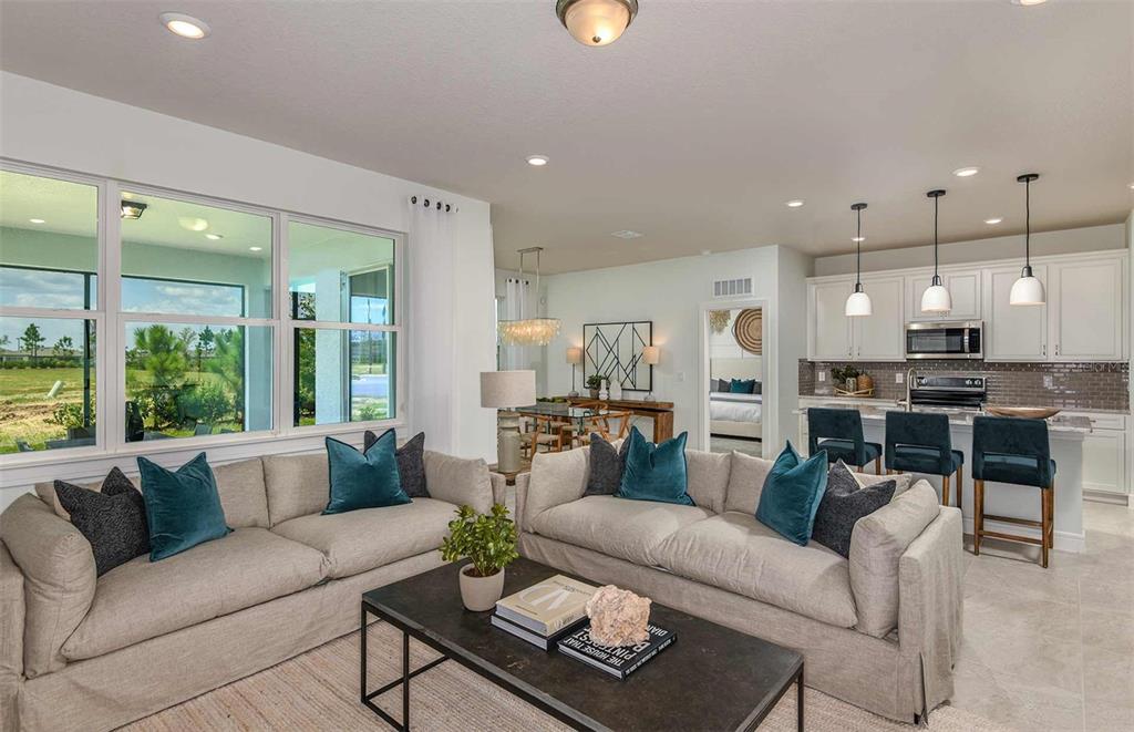 An open-concept living room and kitchen featuring light-colored sofas, a coffee table, and bar seating — 14064 CALICO POINT DRIVE, RIVERVIEW, FL