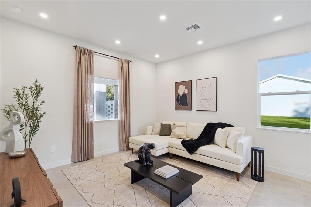 A living room with a white sectional sofa, abstract wall art, and an adjacent dining area — 439 SKYFIELD COURT, LADY LAKE, FL
