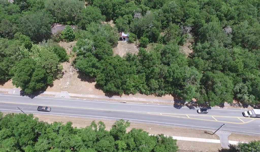 An aerial view shows a wooded lot with a small structure next to a road — 451 ROLLING ACRES ROAD, LADY LAKE, FL