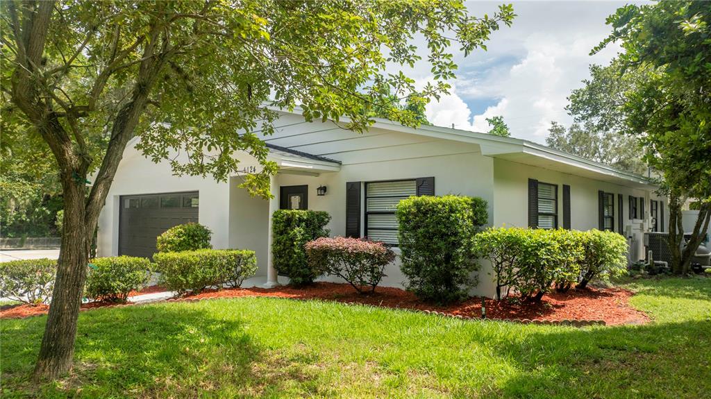 A white, single-story house with a garage, dark shutters, and a landscaped front yard — 1124 MUNSTER STREET, ORLANDO, FL