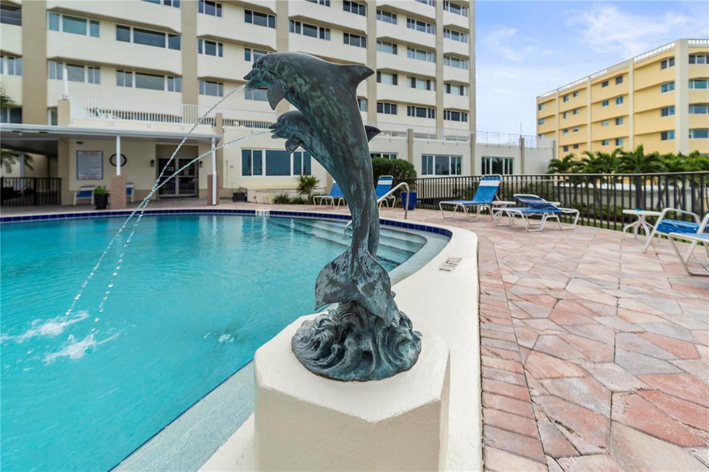 An aerial view shows a multi-story apartment building with a white arrow pointing toward it — 100 BLUFF VIEW DRIVE UNIT 609A, BELLEAIR BLUFFS, FL
