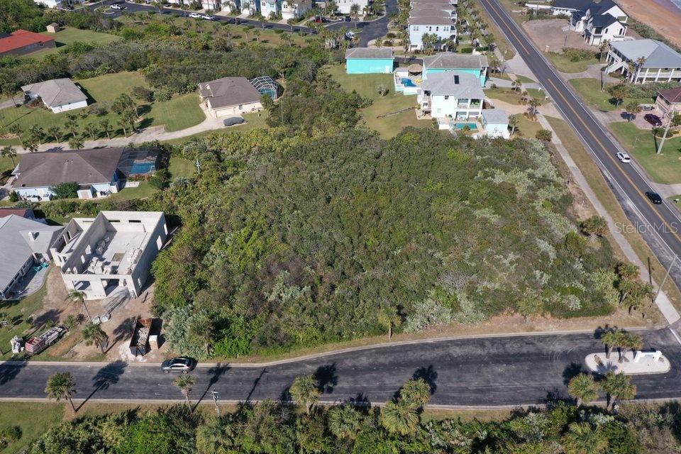 An aerial view shows a wooded vacant lot surrounded by residential houses and a road — 2584 N OCEAN SHORE BOULEVARD, FLAGLER BEACH, FL