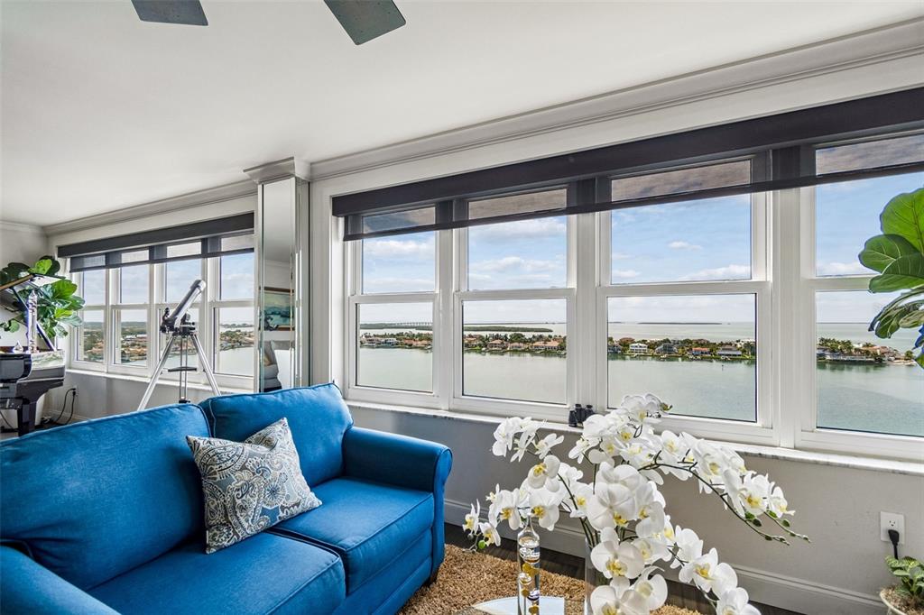 A living room with a blue sofa, white orchids, and large windows overlooking the water — 5200 BRITTANY DRIVE S UNIT 1508, ST PETERSBURG, FL