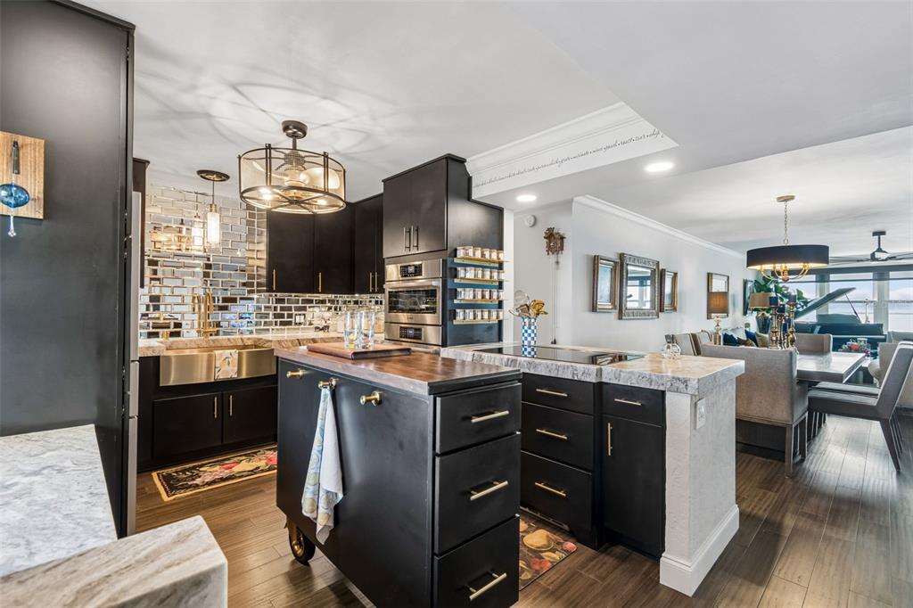 A kitchen features black cabinets, a rolling wooden island, and a mirrored tile backsplash — 5200 BRITTANY DRIVE S UNIT 1508, ST PETERSBURG, FL
