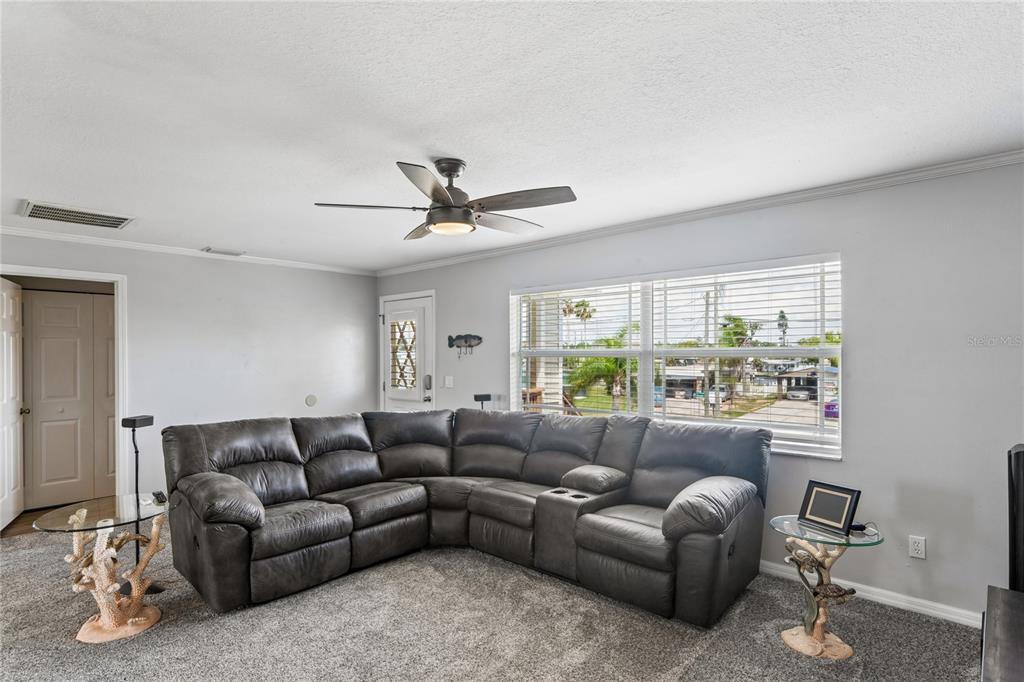 A living room features a large gray sectional sofa, carpeted floors, and a ceiling fan — 6641 BOATYARD DRIVE, HUDSON, FL