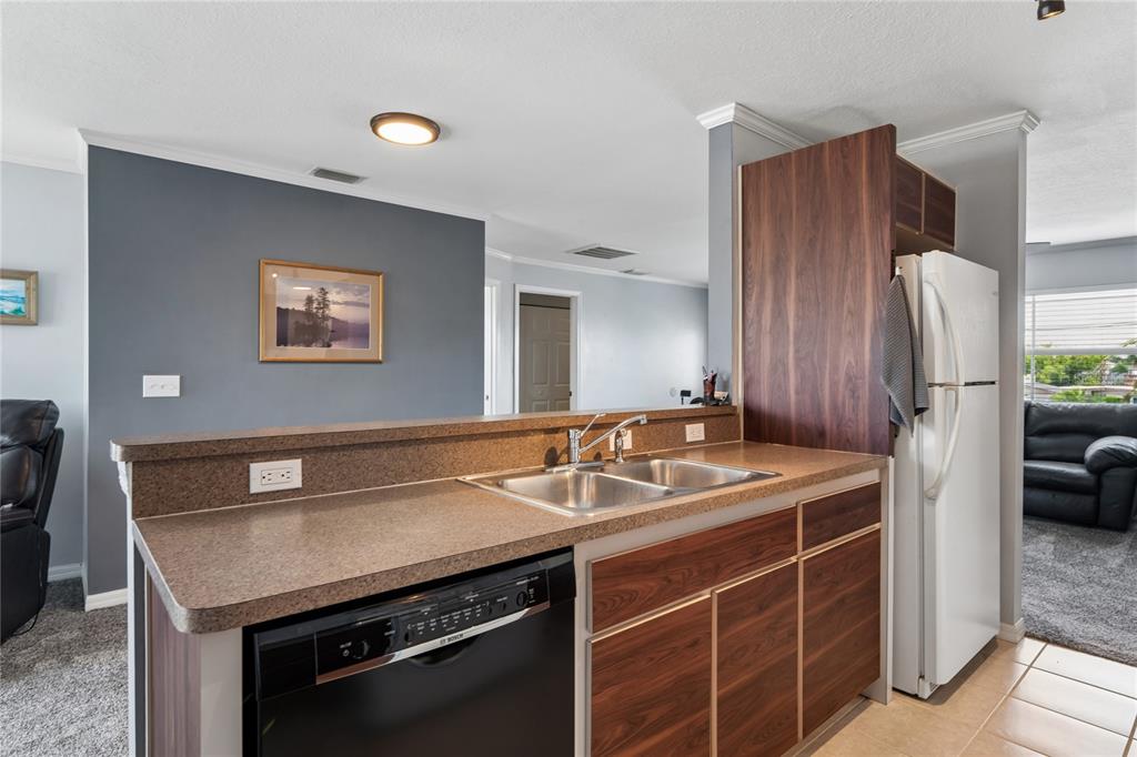 A kitchen features a double sink, dark wood cabinets, a black dishwasher, and laminate countertops — 6641 BOATYARD DRIVE, HUDSON, FL