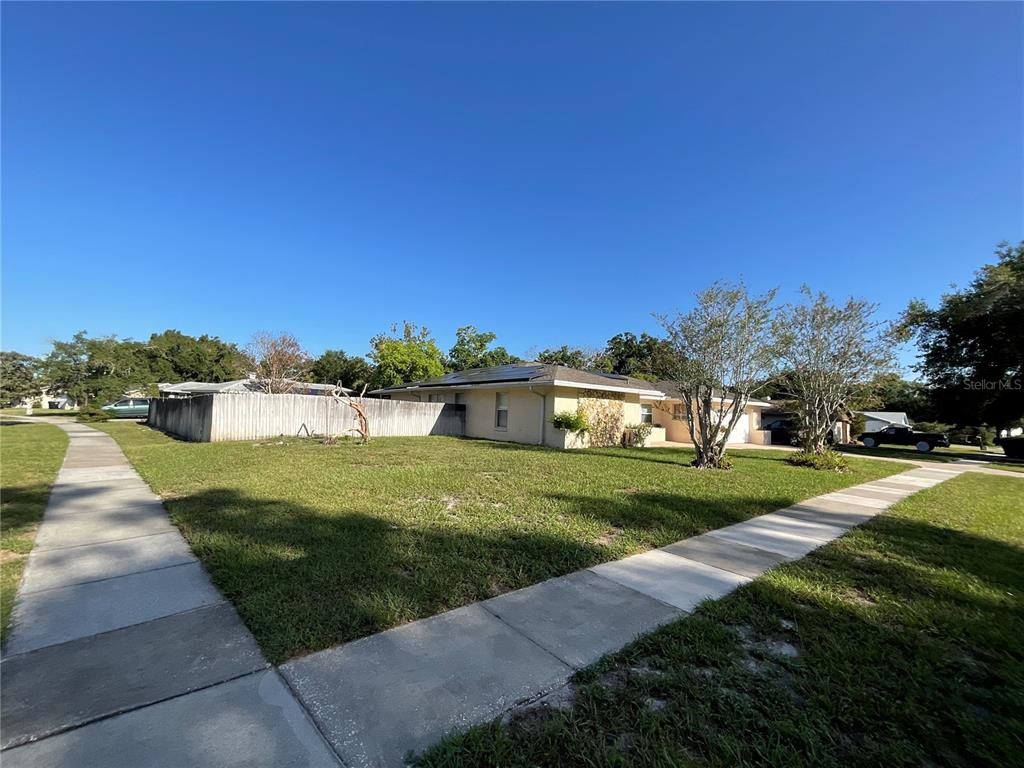 A single-story house with a light-colored exterior and a fenced yard sits on a corner lot — 6004 HARDROCK CIRCLE, ORLANDO, FL