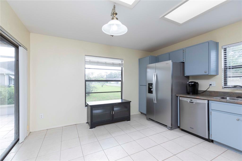 A kitchen with light blue cabinets, stainless steel appliances, tile flooring, and a sliding glass door — 8900 WHISTLER WAY, HUDSON, FL