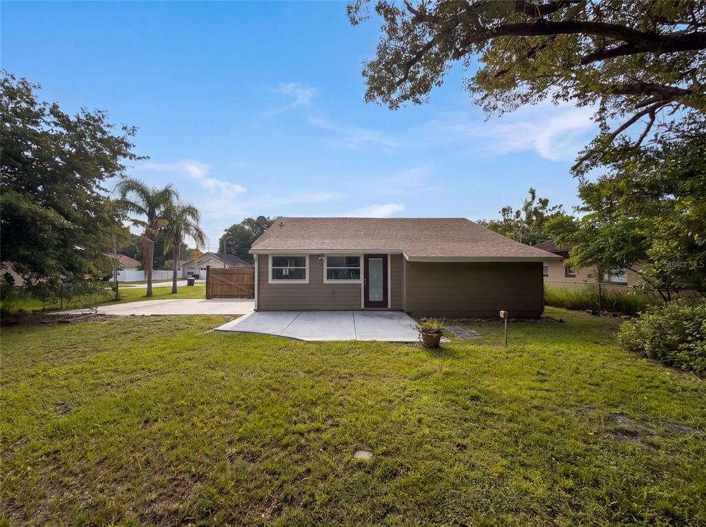 The exterior of a tan house features a concrete patio, a door, and two windows — 718 ALABAMA AVENUE, ST CLOUD, FL
