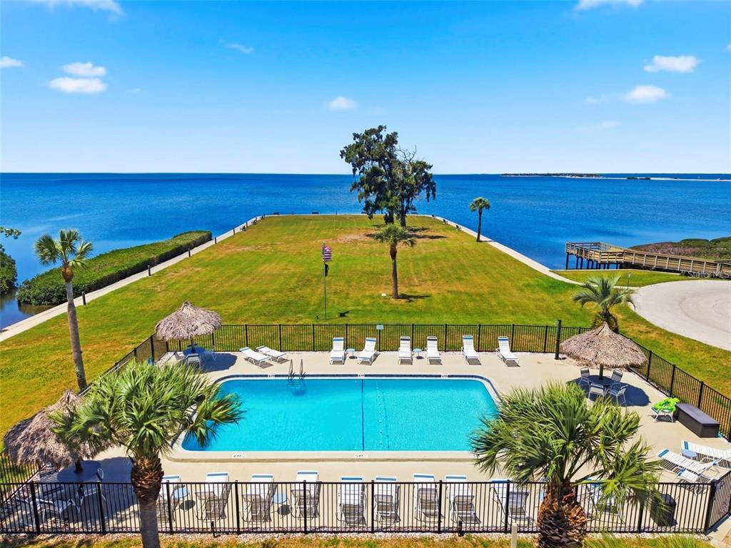 A single-story house with a beige stucco exterior, a shingled roof, and palm trees — 36 WINDRUSH BAY DRIVE UNIT 36, TARPON SPRINGS, FL