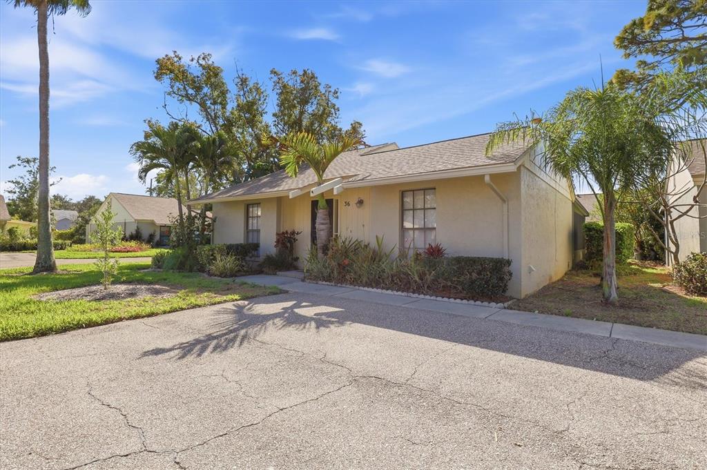 A single-story house with a tan exterior, palm trees, and a green lawn — 36 WINDRUSH BAY DRIVE UNIT 36, TARPON SPRINGS, FL