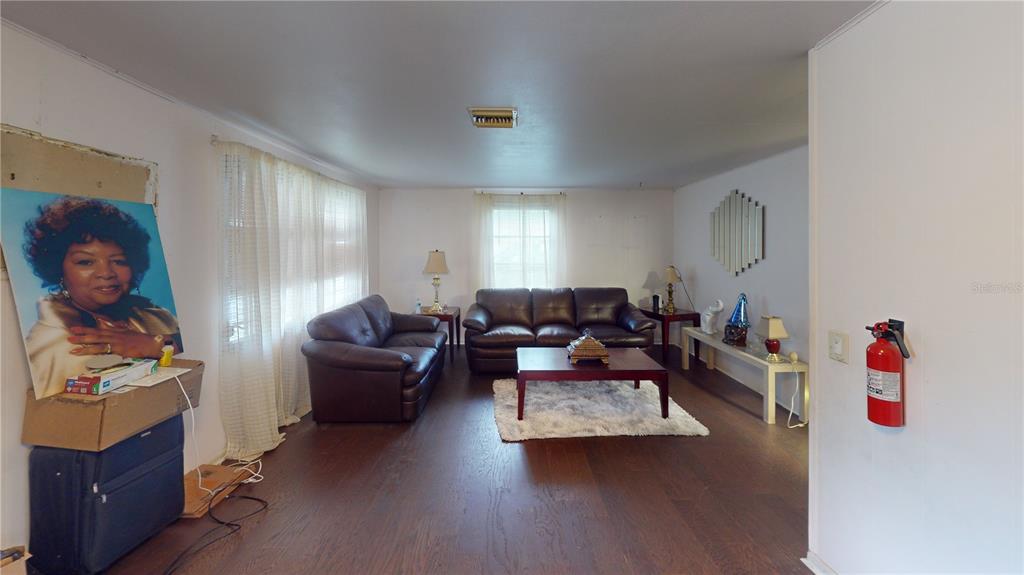 A living room with dark wood floors, two brown leather sofas, and a fire extinguisher — 1721 W NORTH B STREET, TAMPA, FL